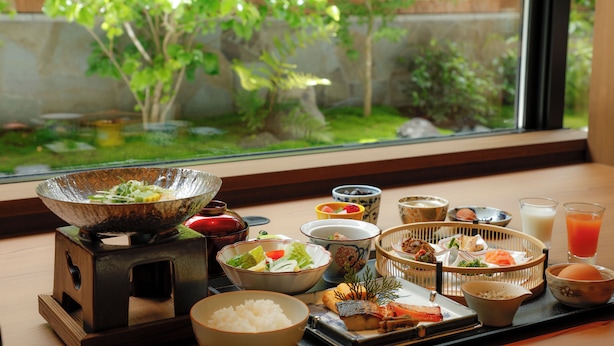 A traditional Japanese meal setup with various dishes and a view of a garden through a window. - Kyoto Omuro Kadensho（Kyoritsu Resorts） (Kyoto)