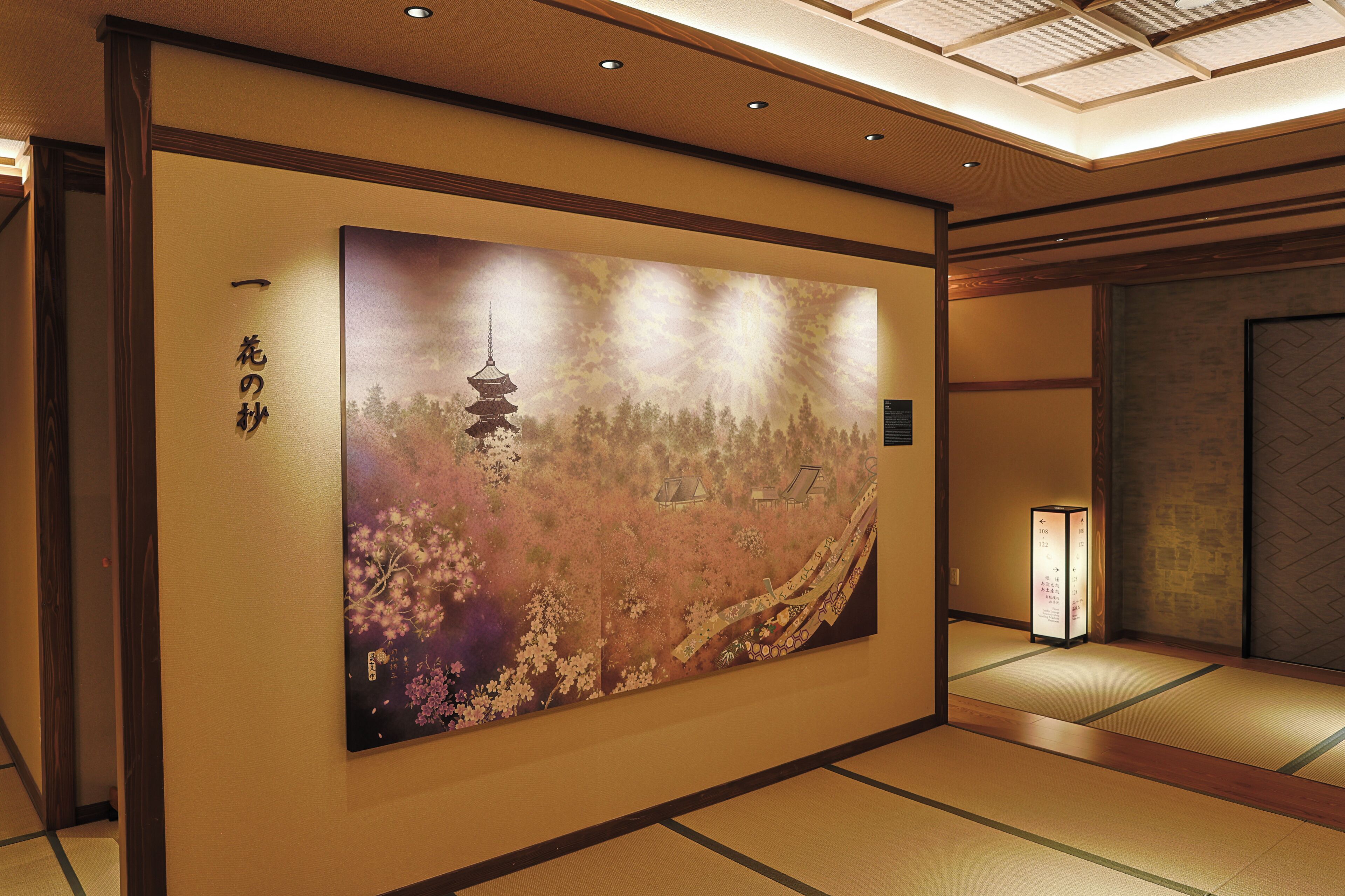 A traditional Japanese interior with tatami flooring, a large wall painting, and a shoji screen.