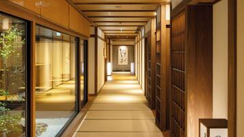 A corridor with tatami mats, wooden sliding doors, and a sign indicating a natural hot spring bath for gentlemen.