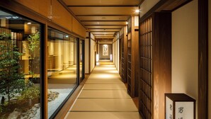 A corridor with tatami mats, wooden sliding doors, and a sign indicating a natural hot spring bath for gentlemen. - Kyoto Omuro Kadensho（Kyoritsu Resorts） (Kyoto)