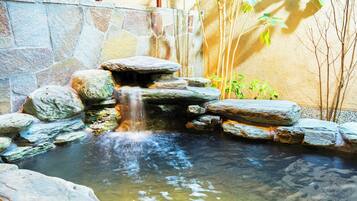 A stone waterfall in a garden with a stone wall and plants.