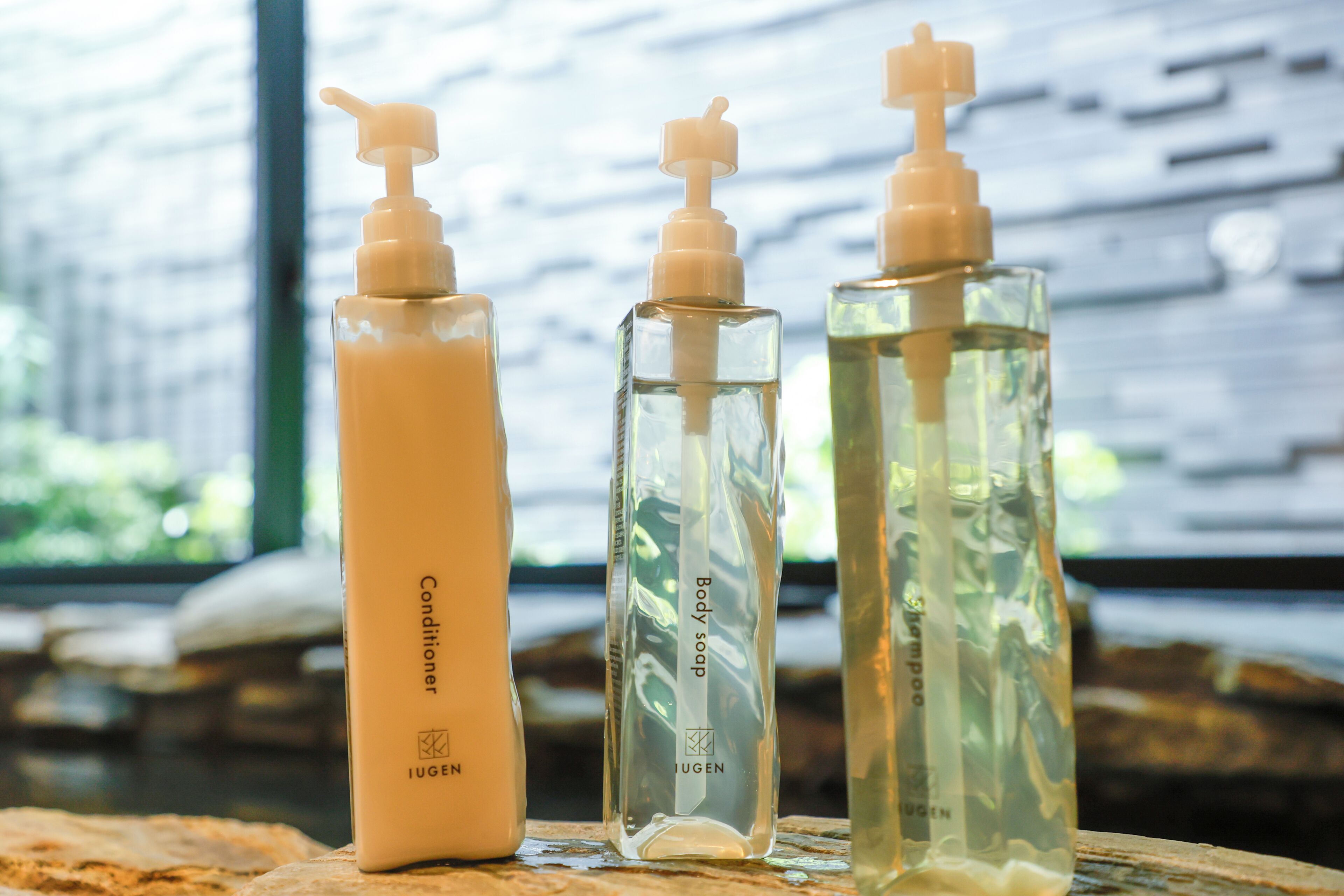 Tres botellas de productos de cuidado corporal sobre una superficie de madera.