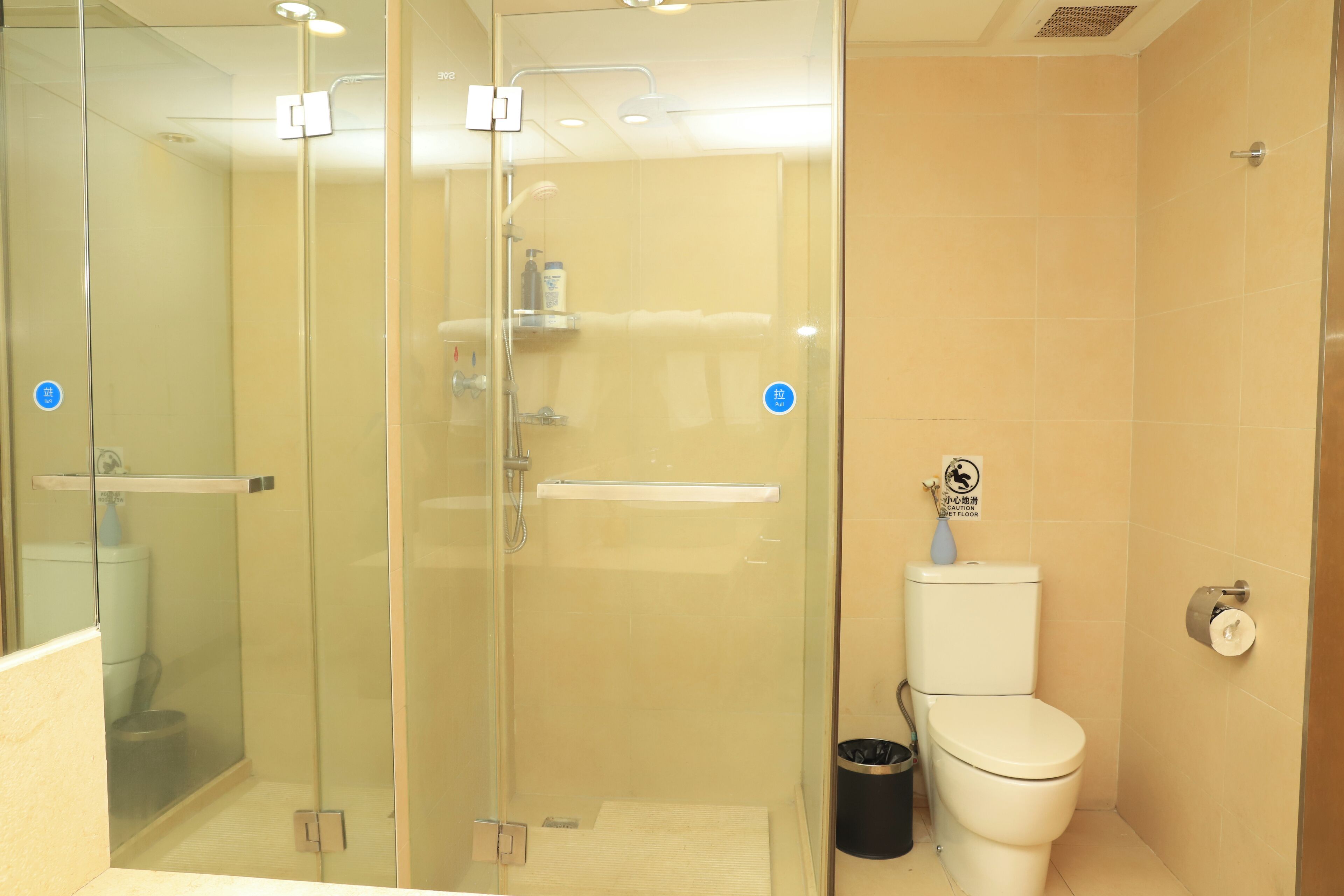 A modern bathroom with a glass-enclosed shower, a toilet, and a sink.
