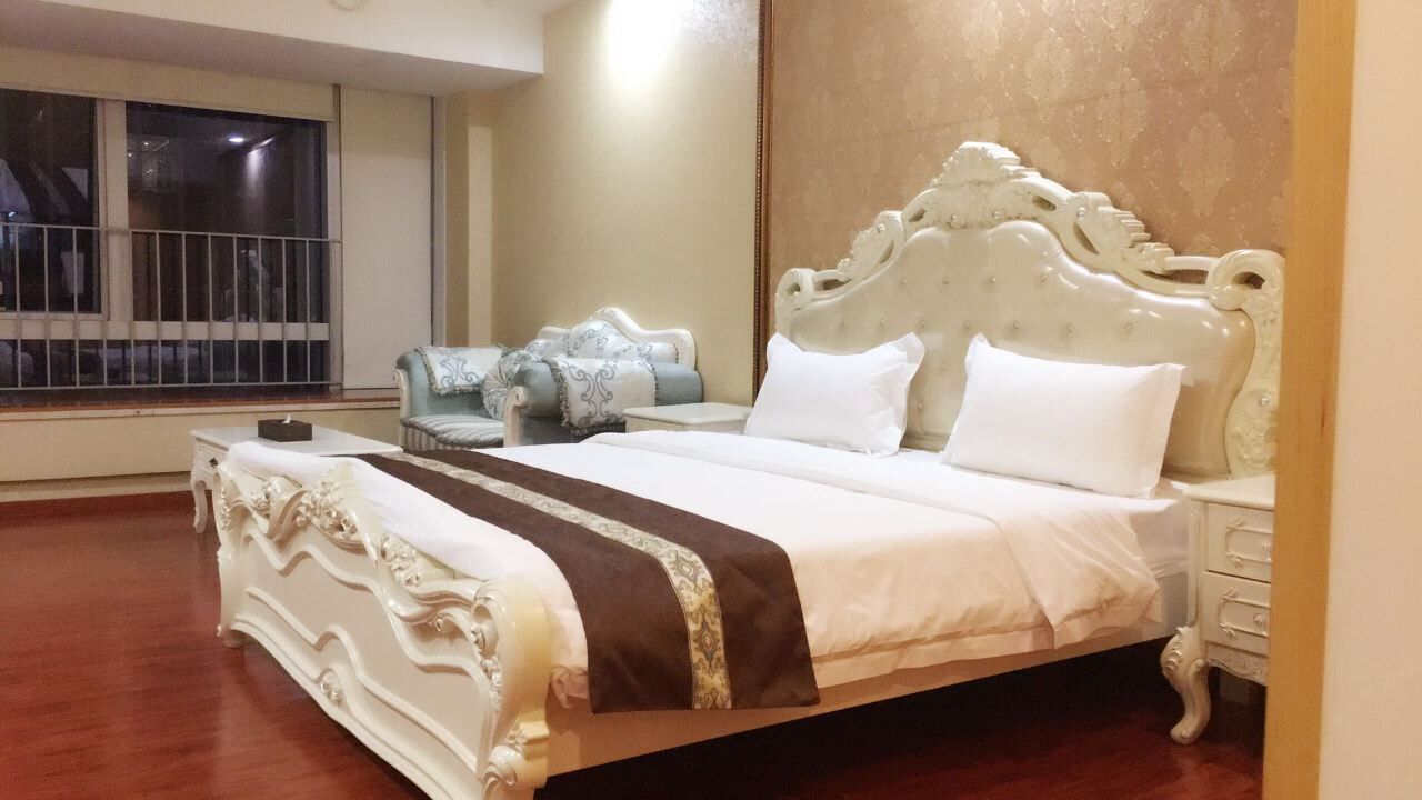 Un dormitorio amplio con una cama grande, una mesita de noche, una silla y vistas al exterior a través de una ventana.