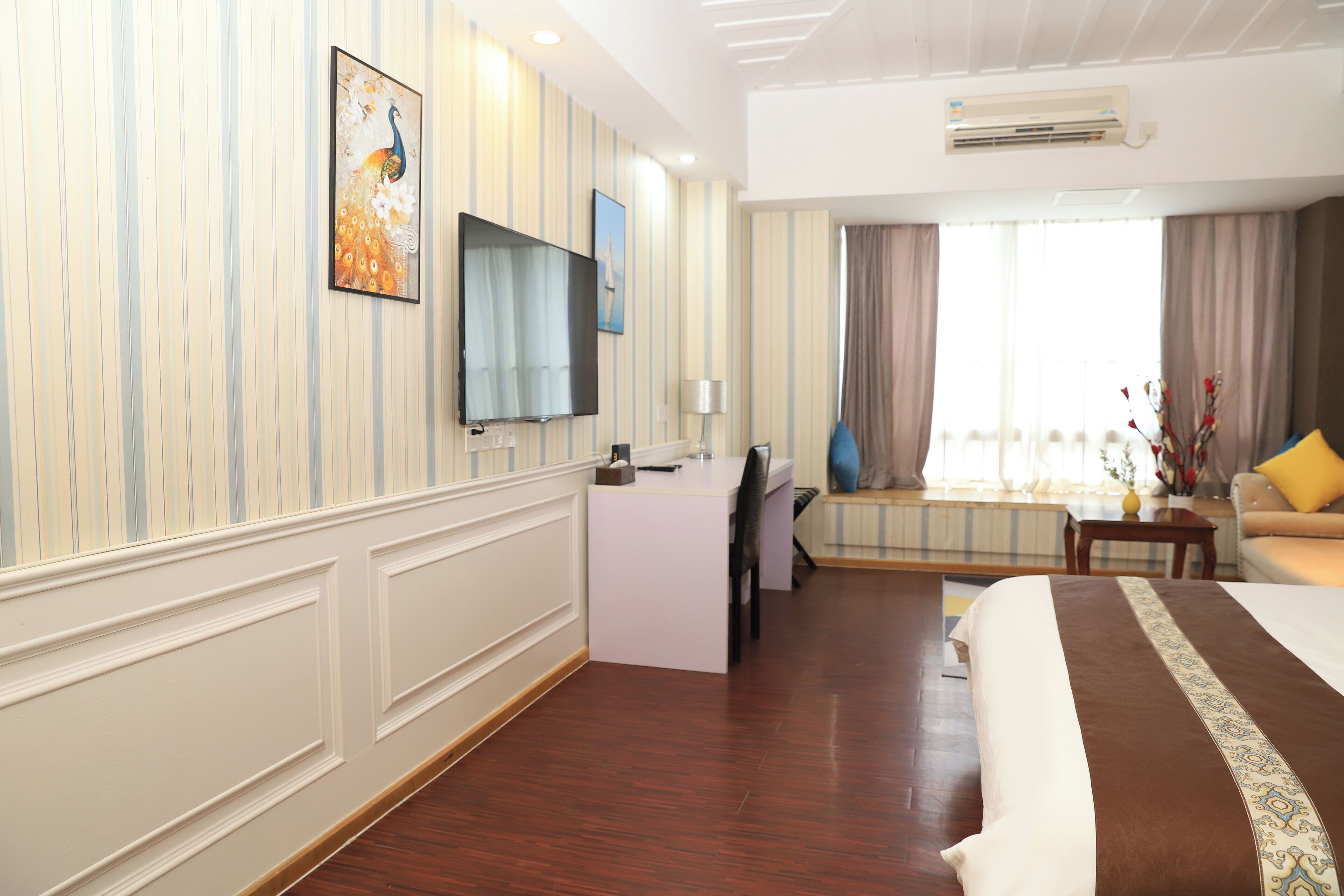 A hotel room with a bed, a desk, a TV, and a window with curtains.
