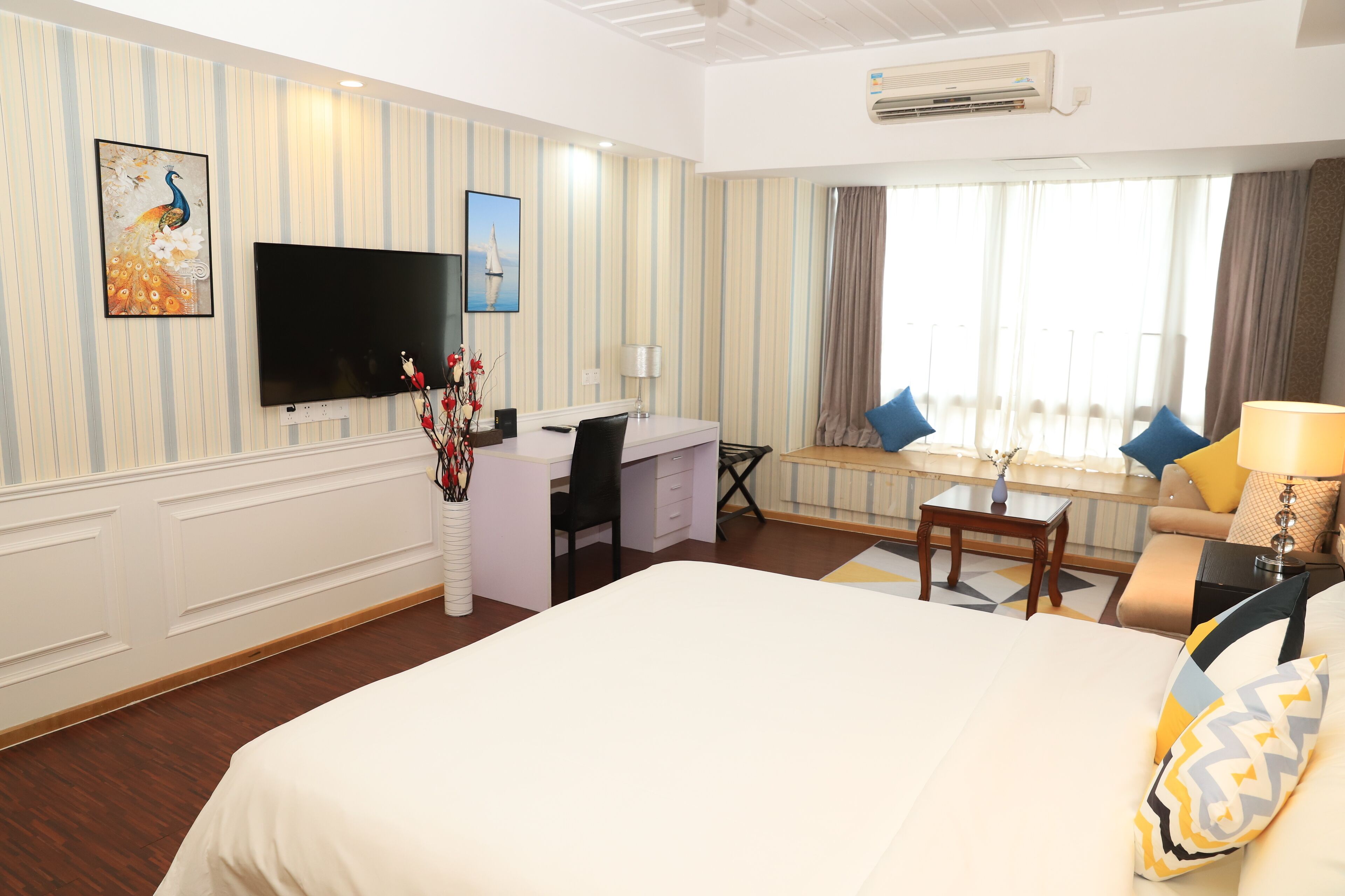 Een hotelkamer met een groot bed, een bureau, een stoel, een televisie en een raam met gordijnen.