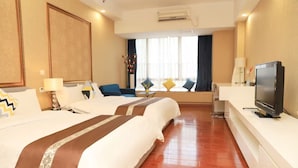 A hotel room with two beds, a TV, a desk, and a window with curtains.