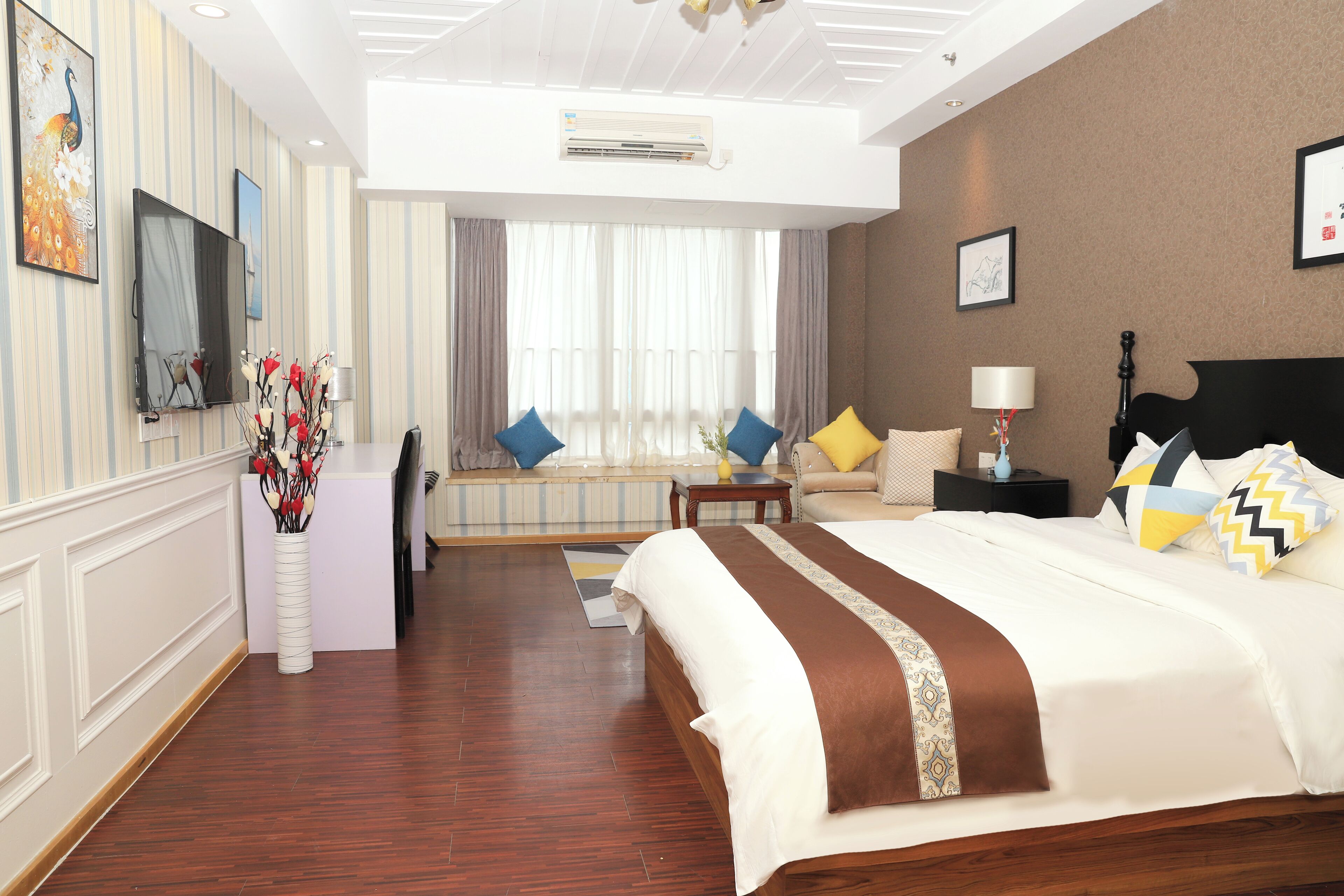 A hotel room with a large bed, a desk, a chair, a TV, and a window with curtains.