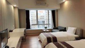 A hotel room with two beds, a desk, a chair, and a window with a view of a building.