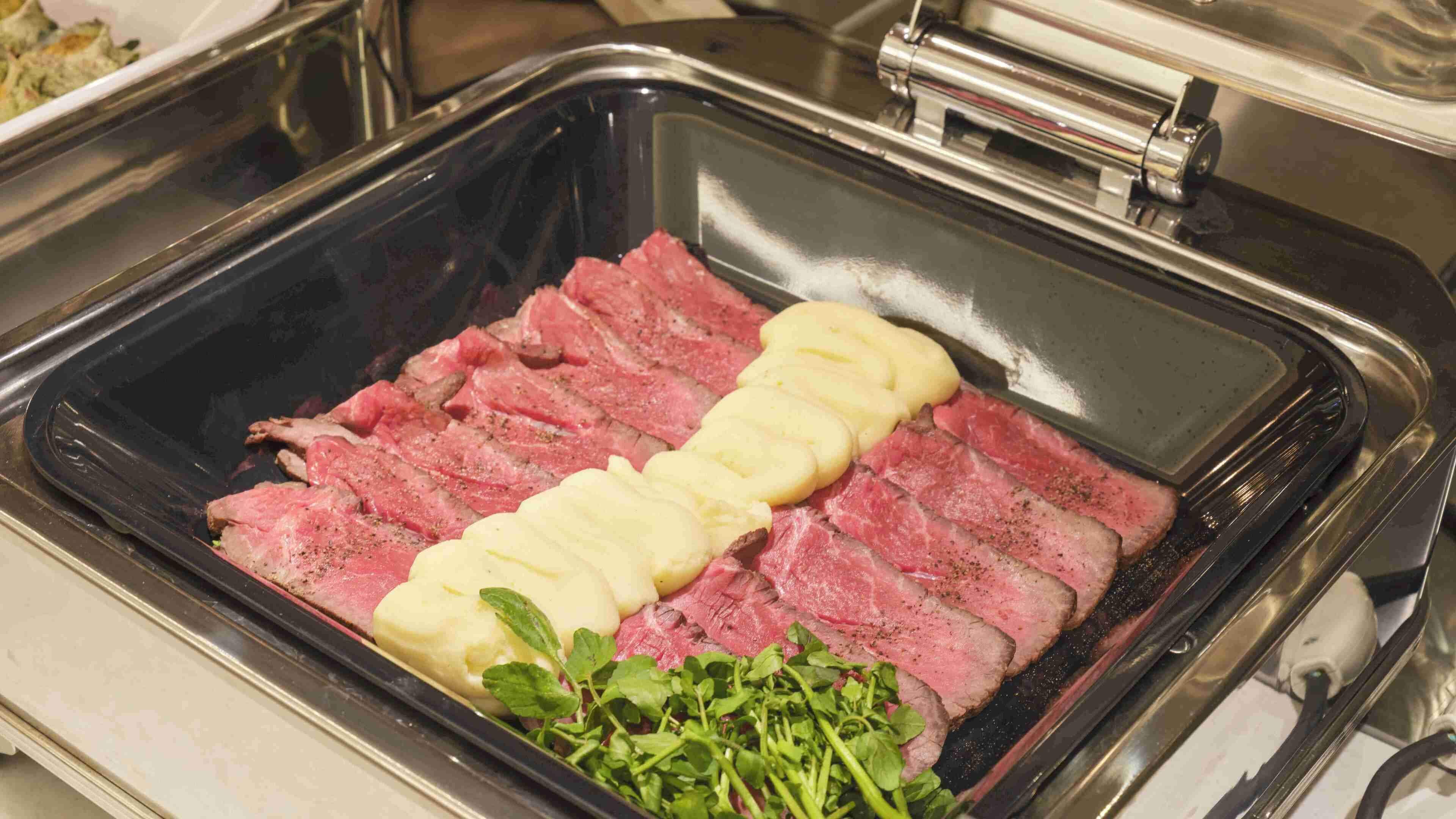 A tray of sliced meat with a garnish of herbs and a yellow spread.