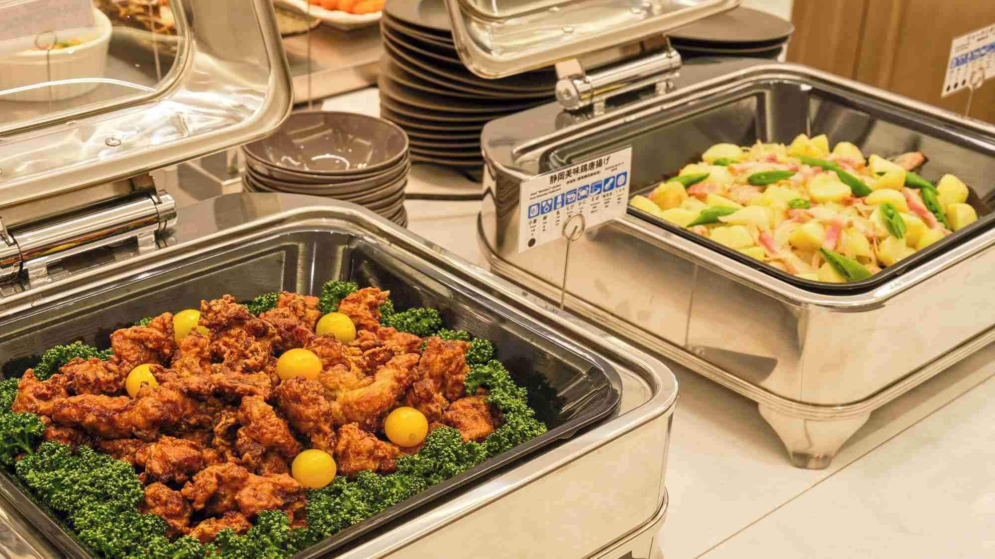 Un bufé con diversos platos, incluyendo pollo frito y una ensalada.
