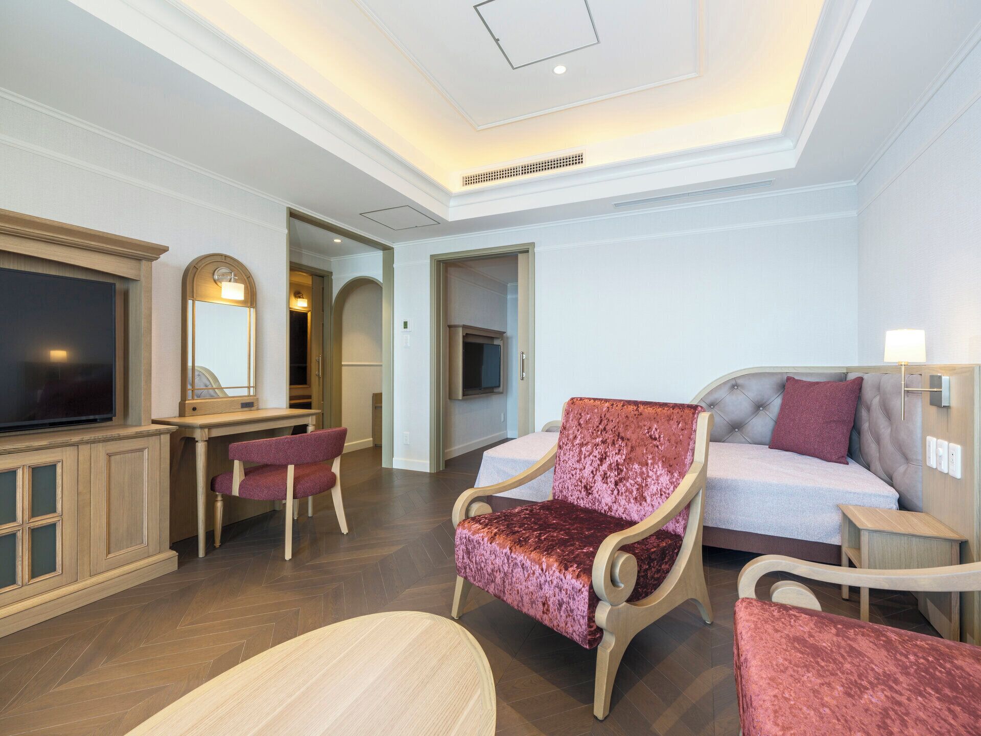 Une chambre d’hôtel moderne équipée d’une télévision à écran plat, d’un bureau, d’un canapé et d’un fauteuil.