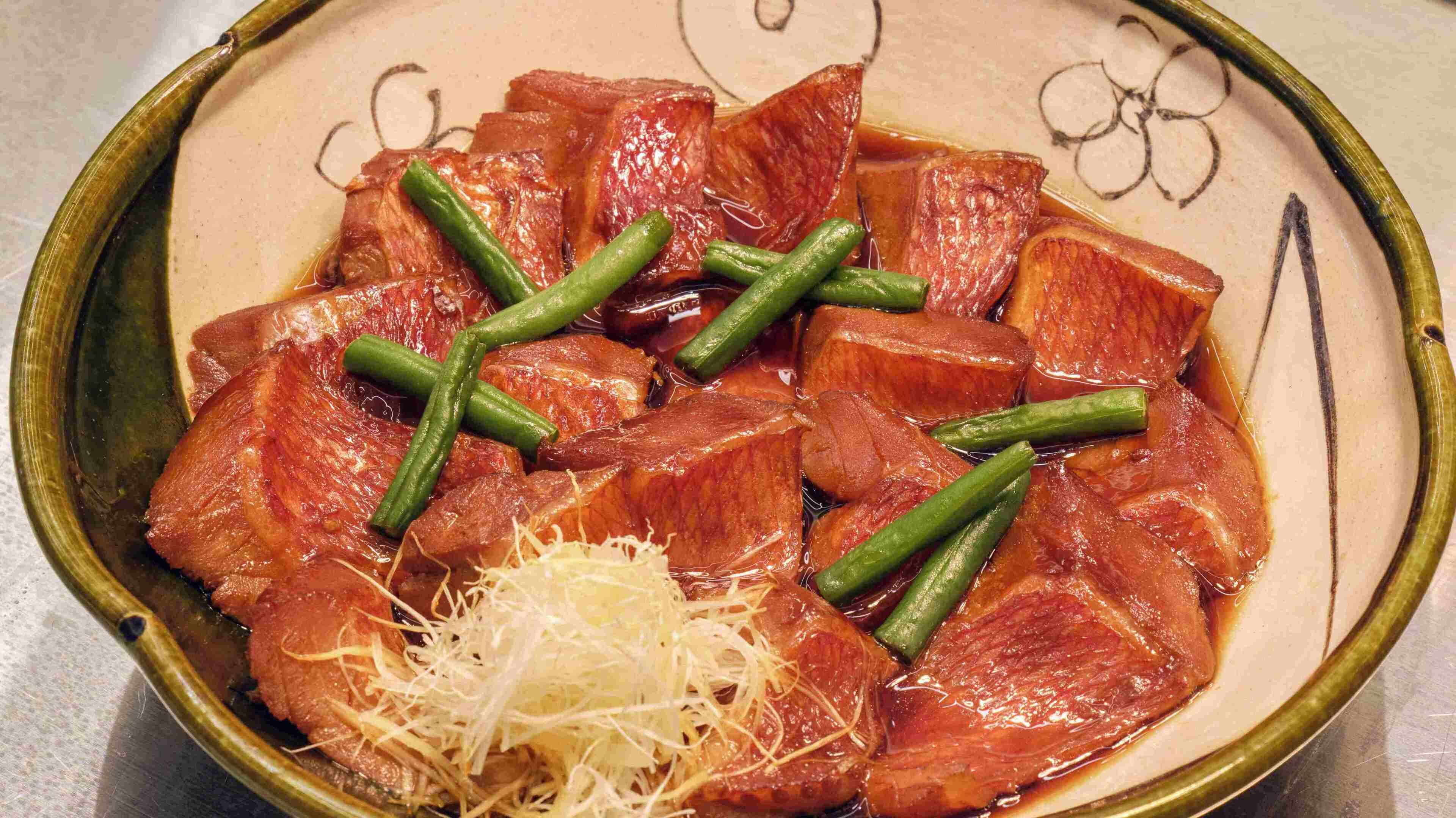 A bowl of sliced meat with green beans and grated cheese.