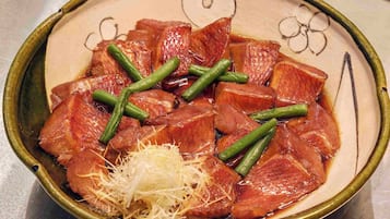 Un plato de carne en rodajas con judías verdes y queso rallado.