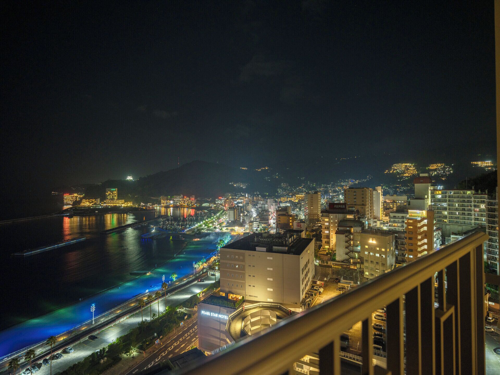 A nighttime cityscape with a river, buildings, and a prominent hotel.