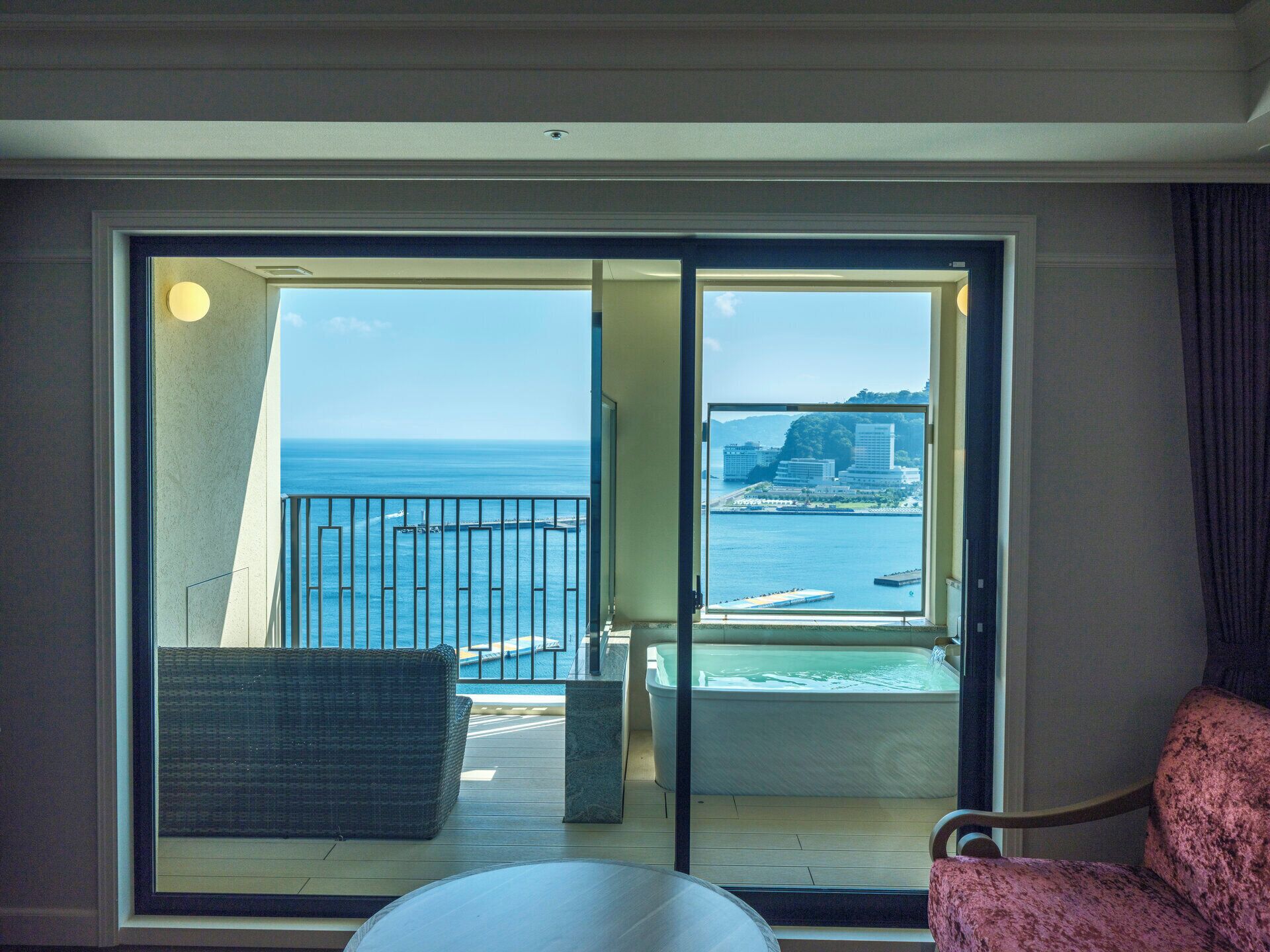 Un balcón con vistas al mar y edificios, una silla y una mesa.