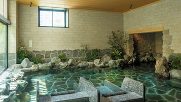 Un espace de détente avec un mur en pierre, une petite cascade et des sièges installés au bord de l’eau.