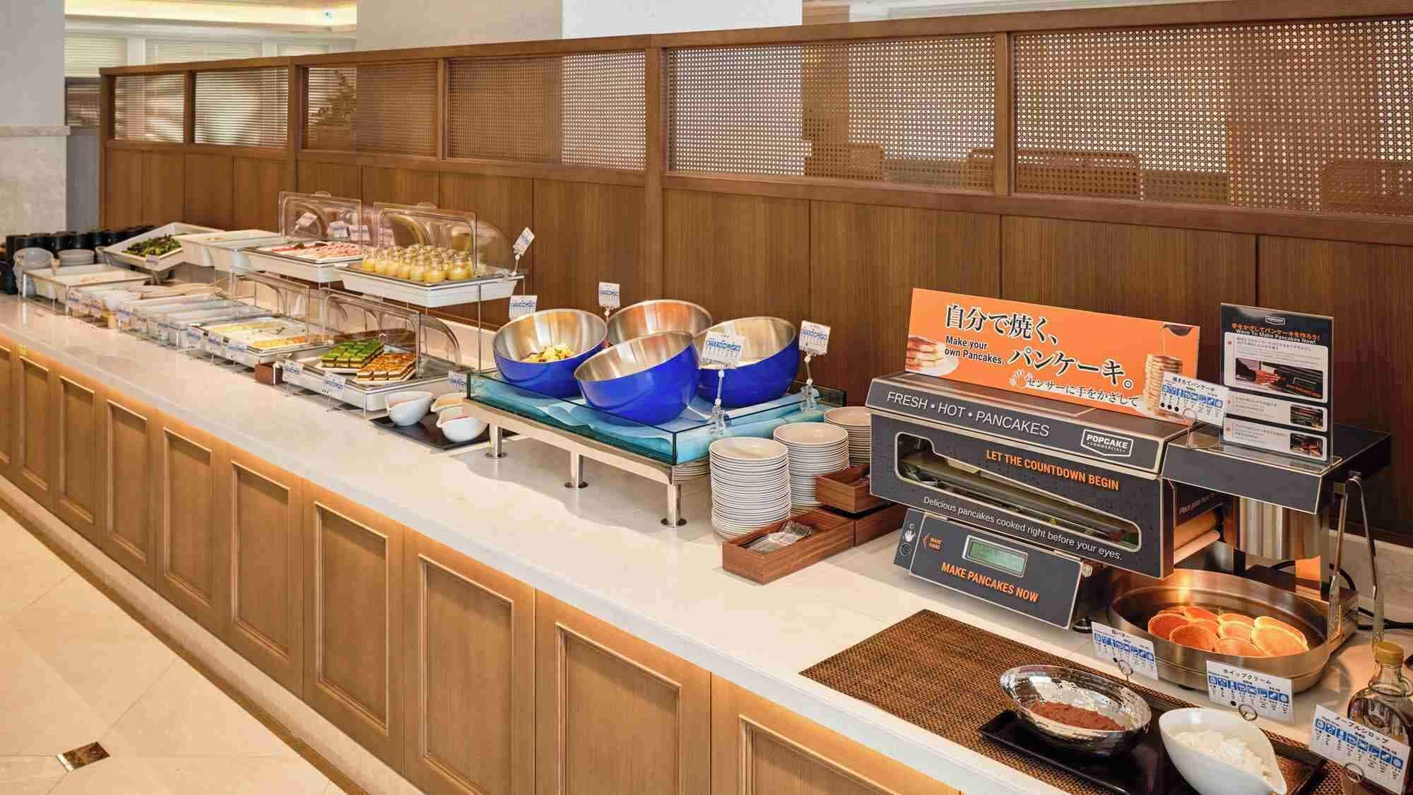 A buffet setup with various food items and a pancake station.