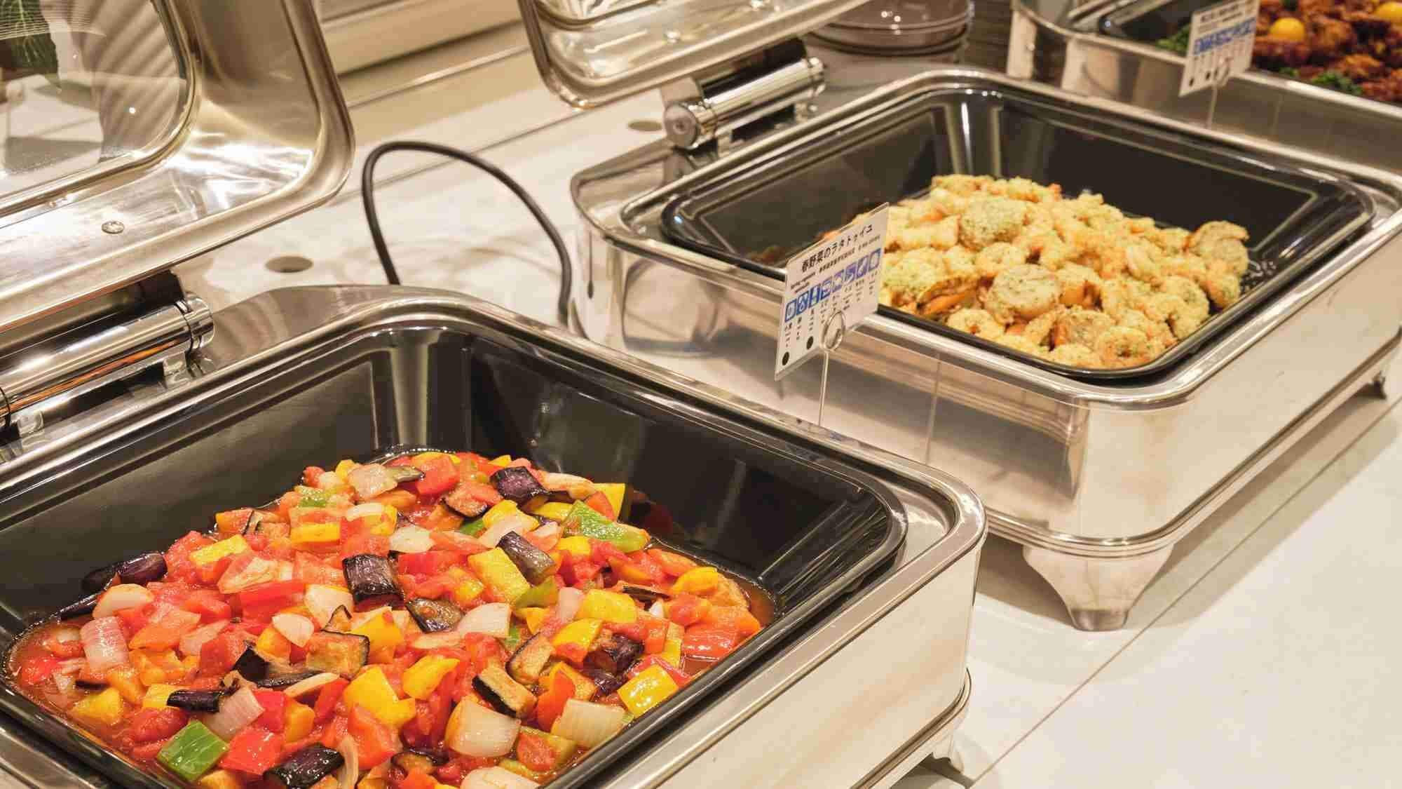 Un bufé con diversas opciones de comida, incluyendo una mezcla de verduras, un plato de mariscos y un pastel de mariscos.