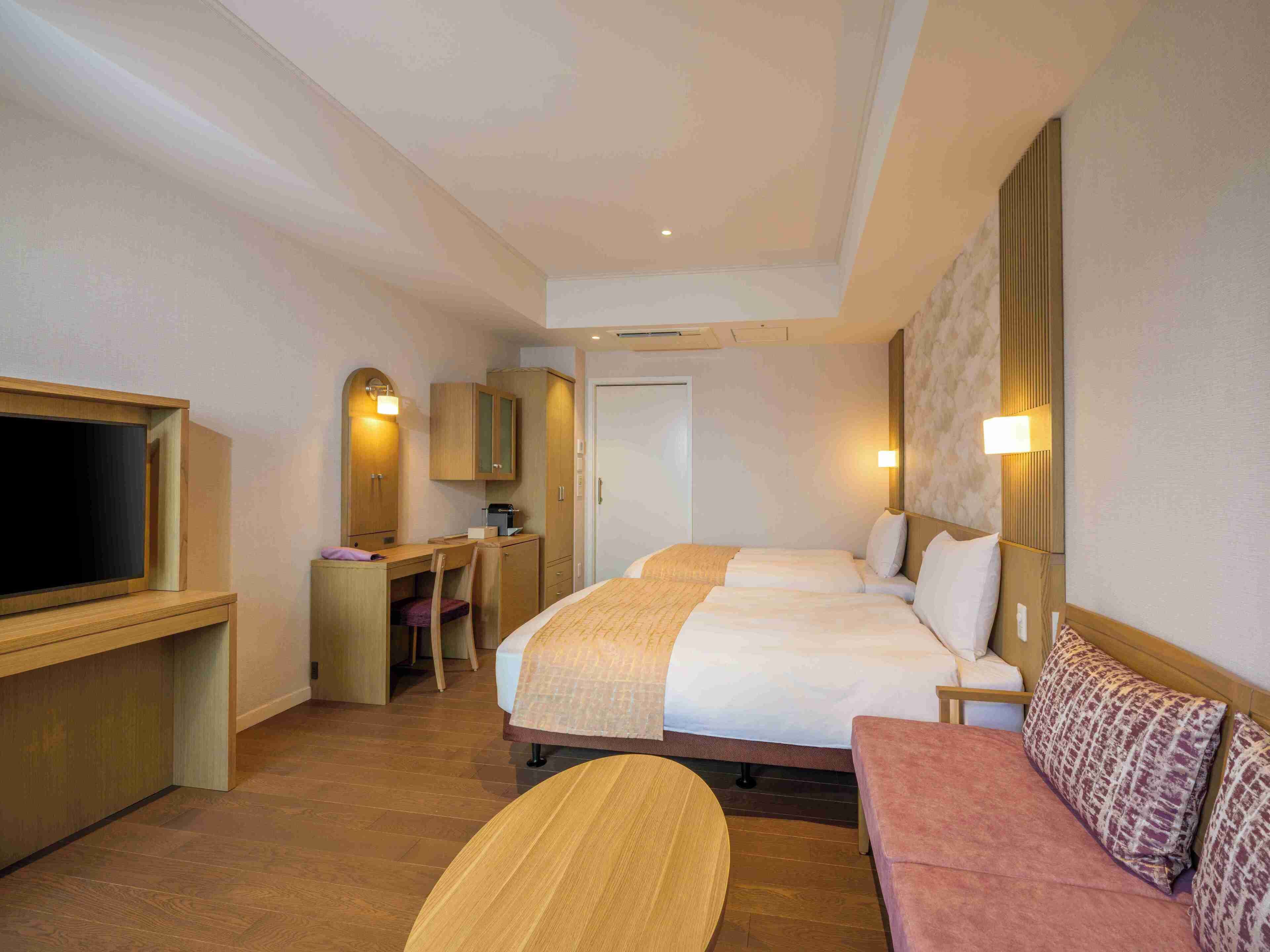Una habitación de hotel con cama, escritorio, televisor y sofá.