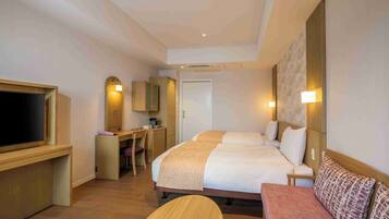 Una habitación de hotel con cama, escritorio, televisor y sofá.