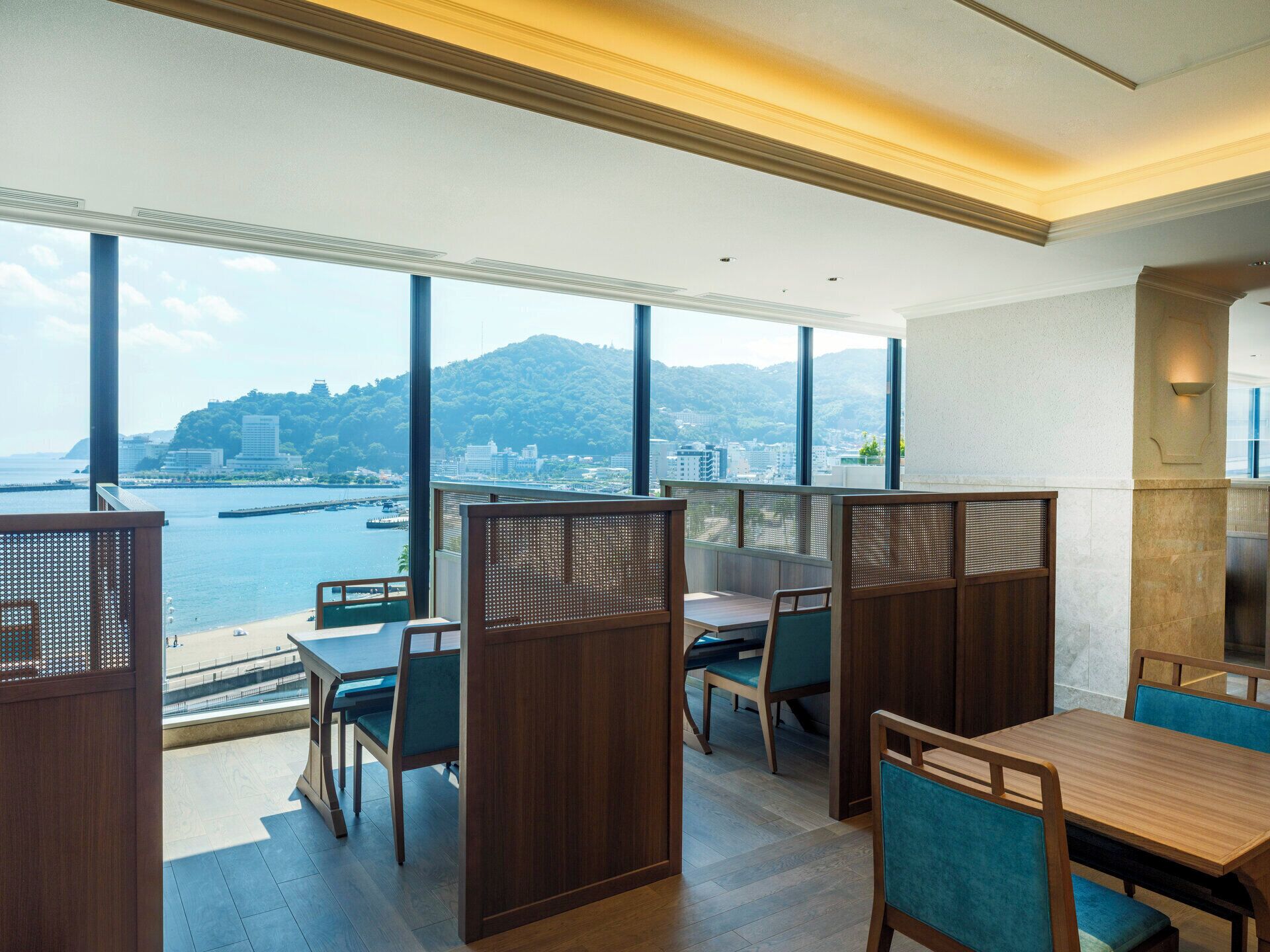 Un espace de restauration moderne doté de grandes fenêtres offrant une vue panoramique sur le paysage urbain de la côte.