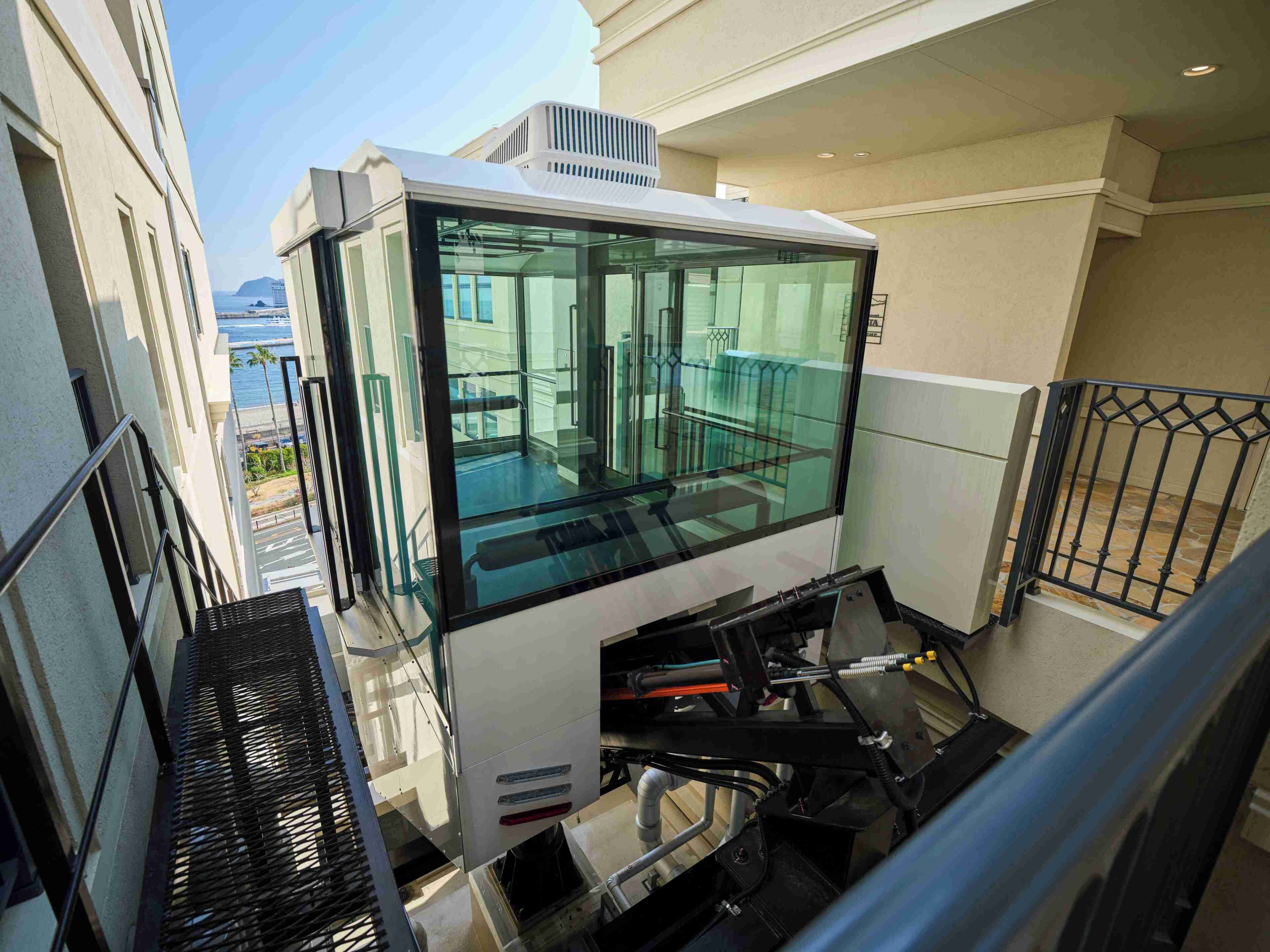 Un ascensor moderno con puertas de vidrio y barandales de metal.