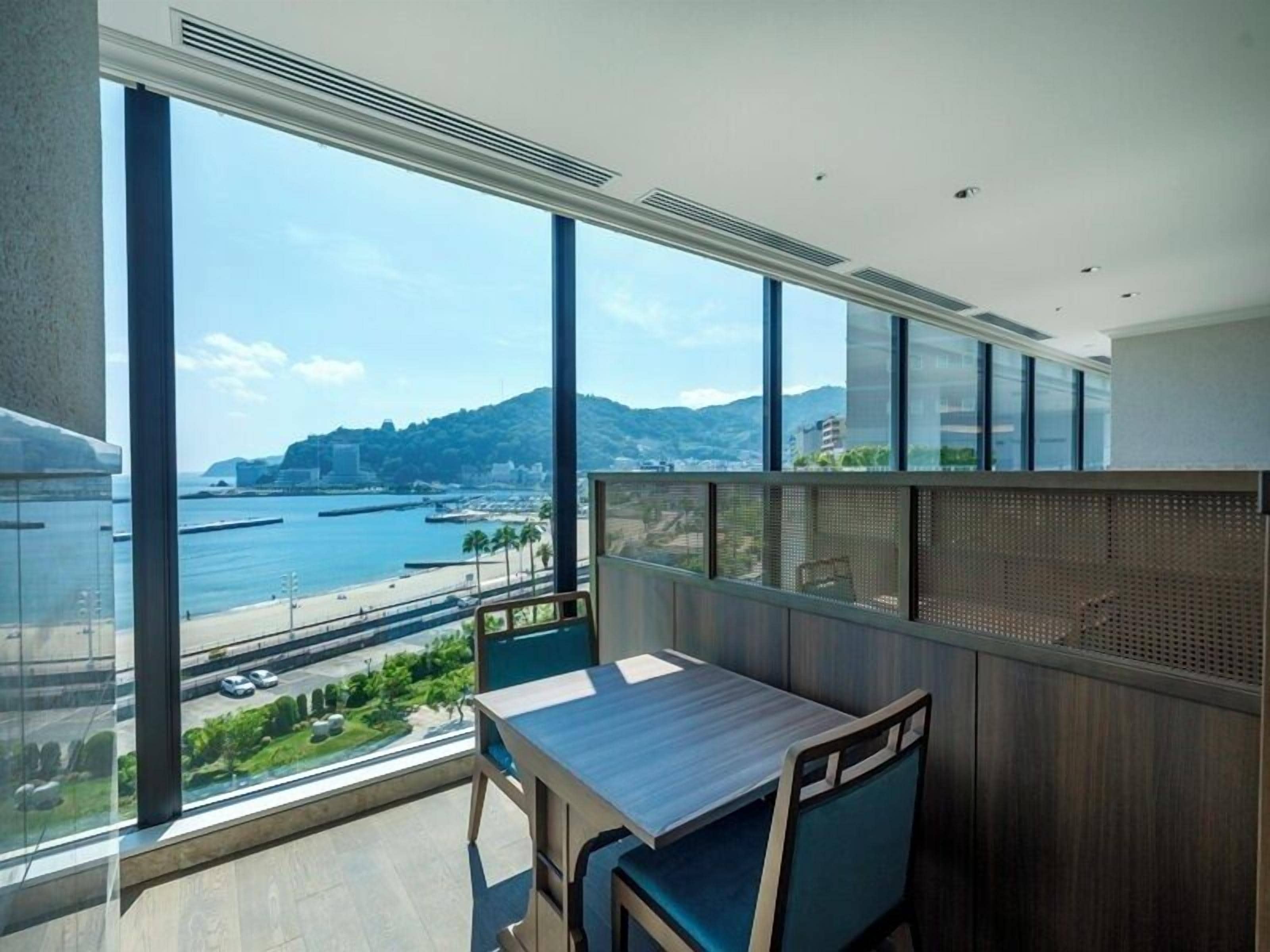 Un balcón con vistas a la costa, una mesa y una silla.