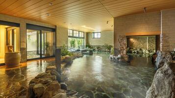 Un área de spa con aguas termales, paredes de piedra y techo de madera.