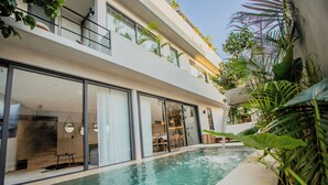 A modern building with a swimming pool, large windows, and indoor plants. - Niña Bonita, Tropical Villa 5 min from Tulum beach great location (Tulum)