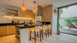 A modern kitchen with a central island, bar stools, hanging lights, and a view of the outdoors. - Niña Bonita, Tropical Villa 5 min from Tulum beach great location (Tulum)