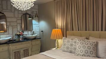 Une chambre à coucher avec un grand lit, un lustre, une coiffeuse avec un miroir et une lampe.