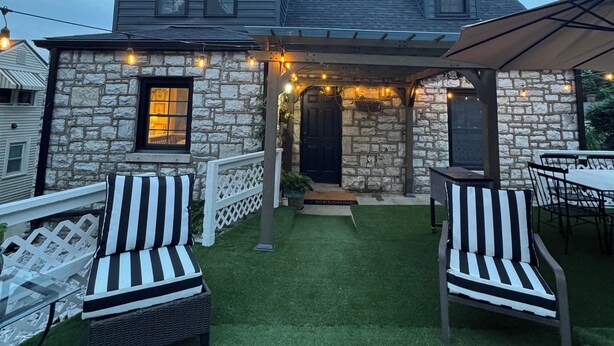 Una casa de piedra con un porche cubierto, mobiliario exterior e iluminación con guirnaldas.