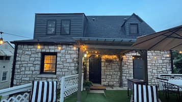 Une maison en pierre dotée d’un patio couvert, de meubles d’extérieur et de guirlandes lumineuses.