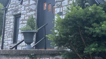 Un bâtiment en pierre avec une porte sombre, un pot de fleurs et un escalier.