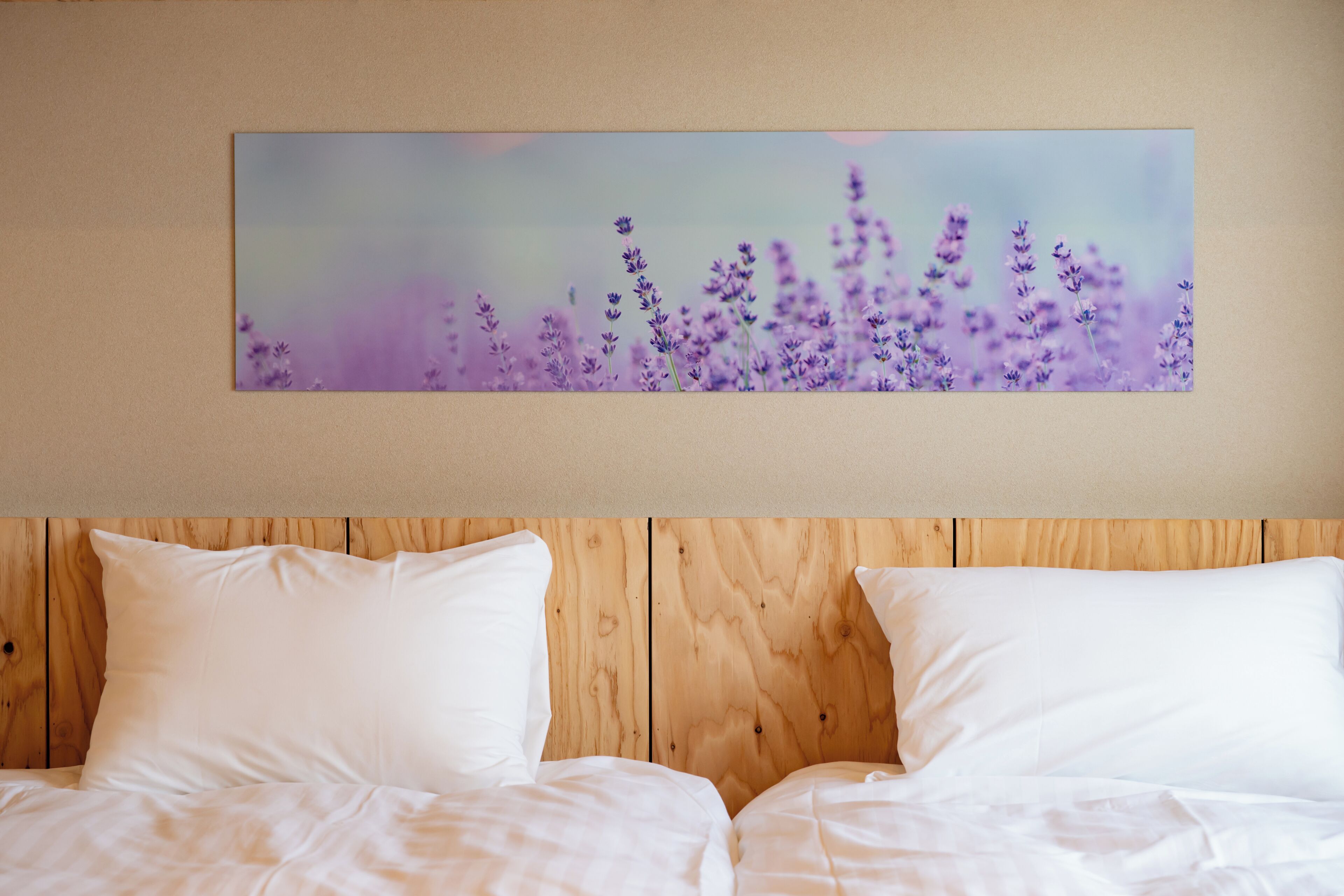 A bedroom with a wooden headboard, two white beds, and a lavender floral painting on the wall.