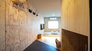 A modern bathroom with wooden walls, a black floor, and a visible shower area. - JR Mobile Inn Furano (Furano)