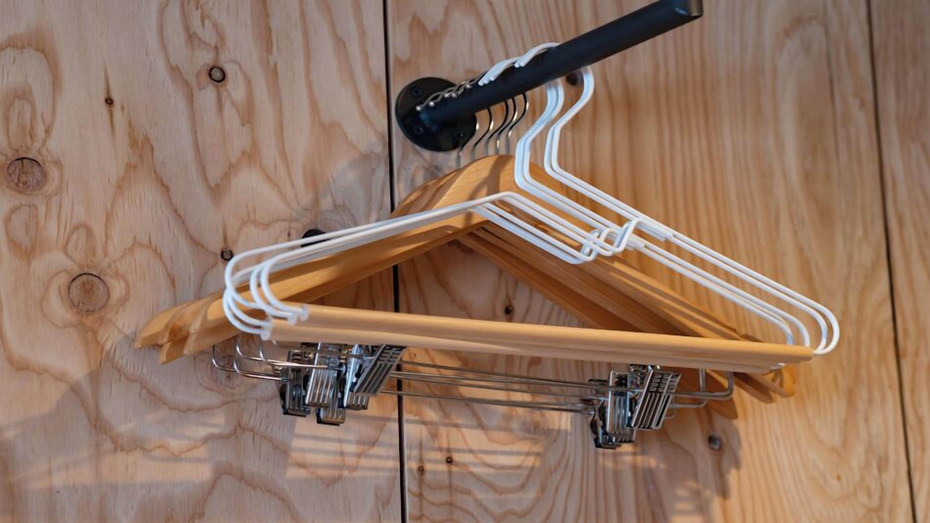 A wooden hanger with a metal frame and a black handle on a wooden floor.