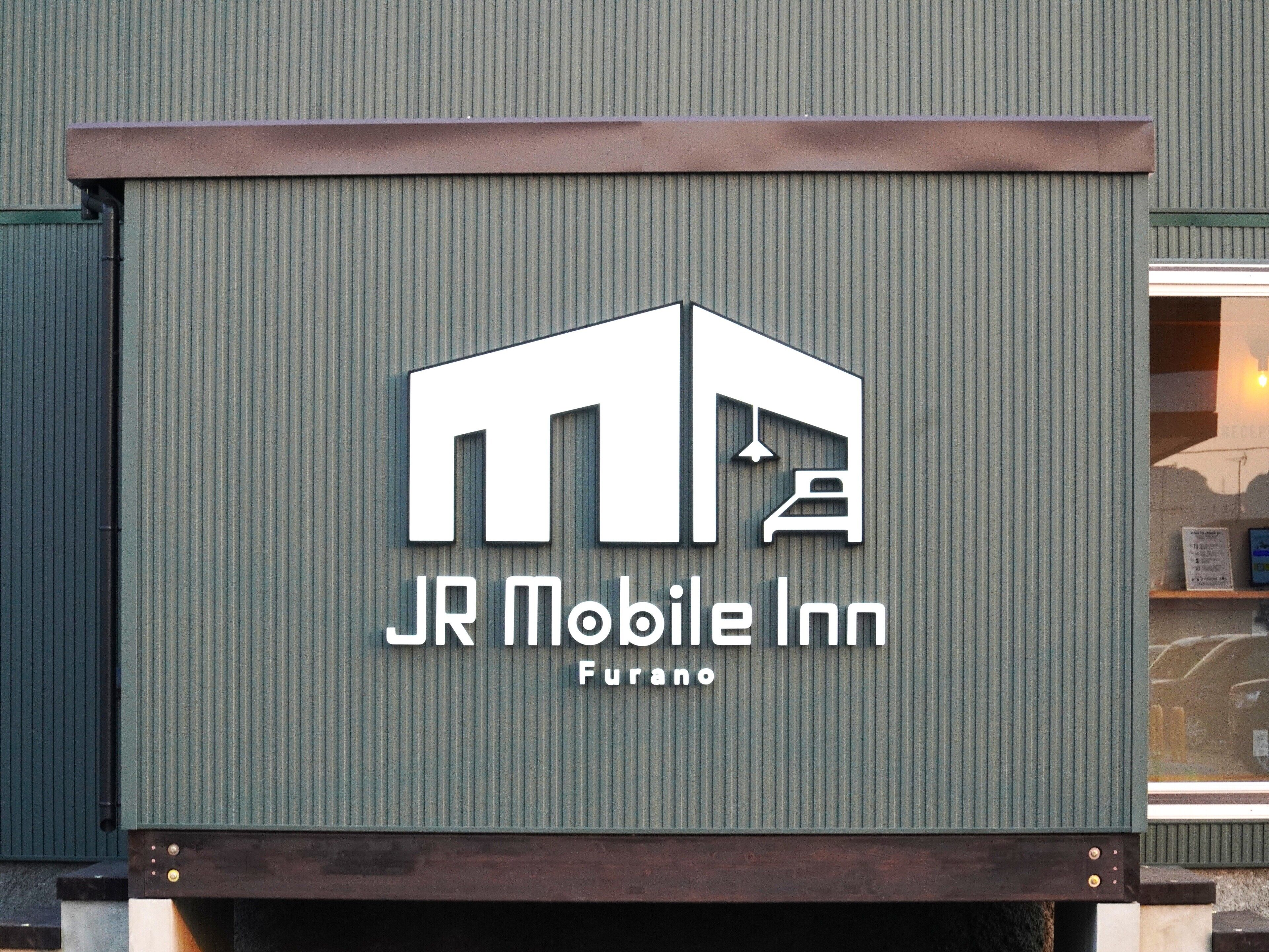 Une enseigne pour le JR Mobile Inn à Furano, avec un logo simple et le nom de l’établissement.