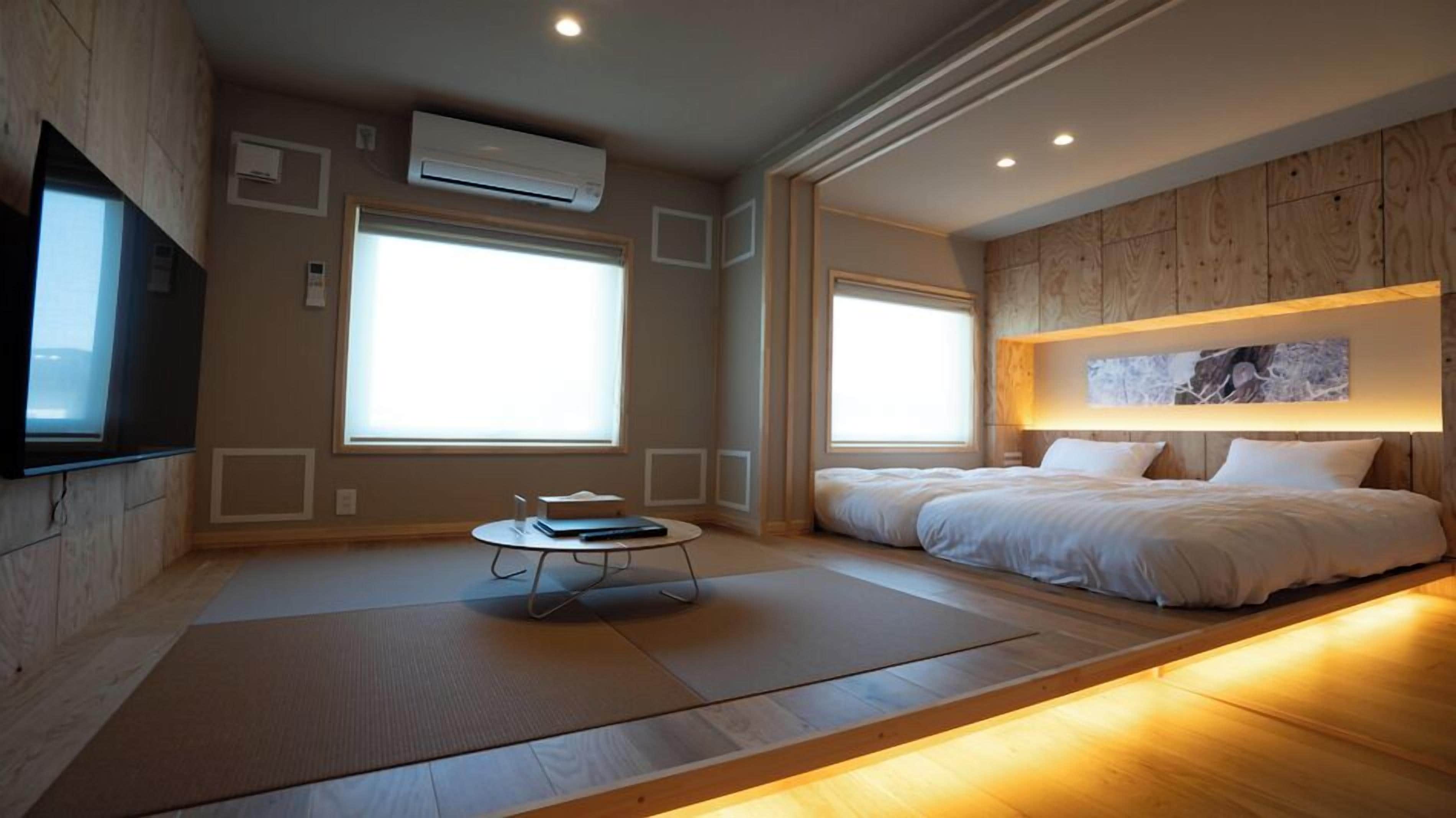 Ein modernes Schlafzimmer mit einem großen Bett, einem kleinen Tisch und einem großen Fenster.