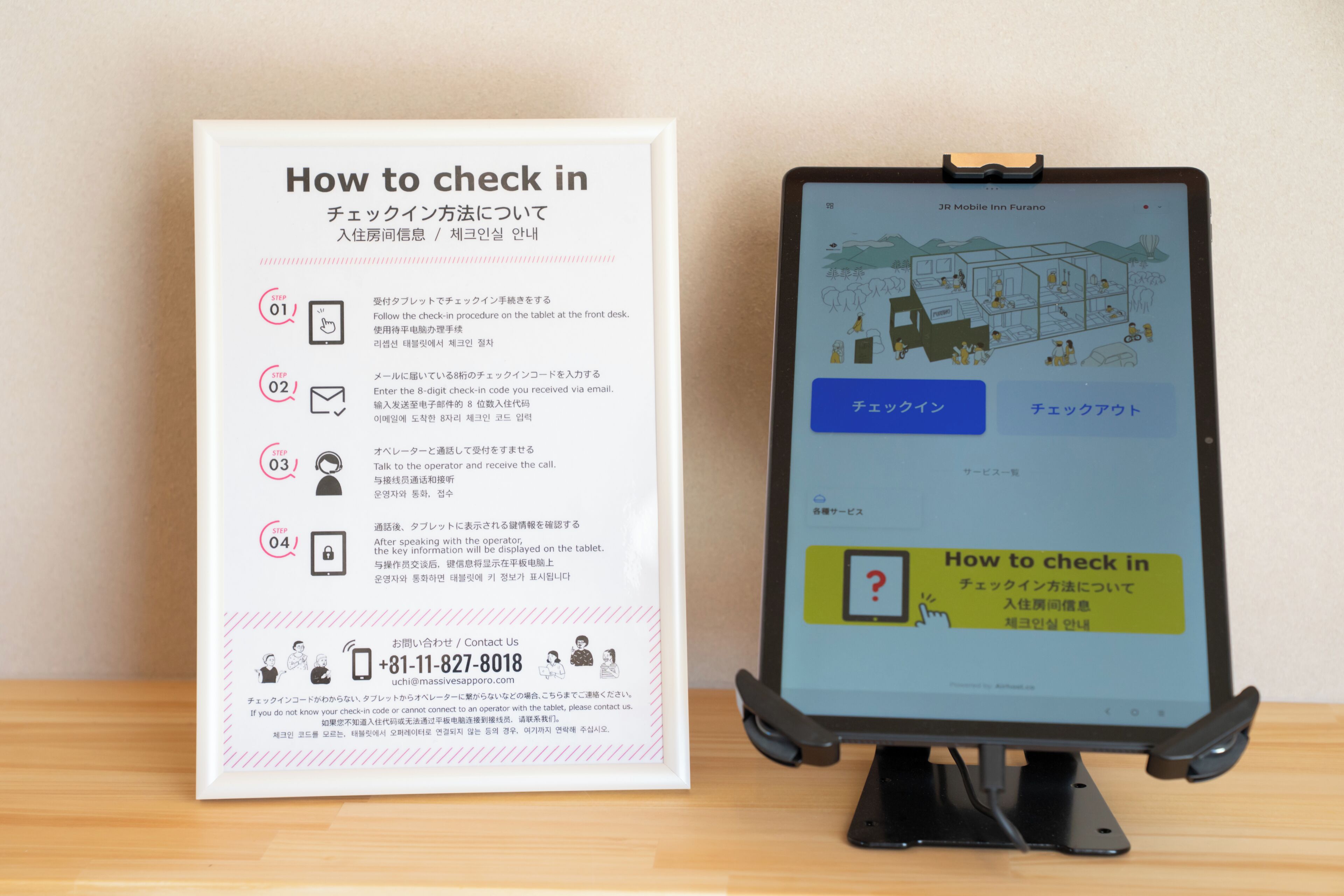 A sign with instructions on how to check in at a hotel, accompanied by a tablet displaying a similar check-in process.