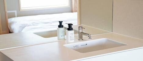 A hotel bathroom with a white sink, a mirror, and two bottles of toiletries.