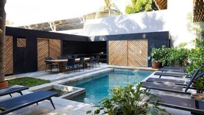 Un espace piscine extérieur moderne, doté de chaises longues, d’une table à manger et d’une petite piscine.