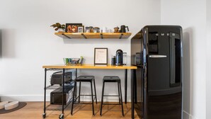 A compact kitchen with a black refrigerator, a wooden countertop, and two black stools. - Modern Harbor Stay | Steps to Tours & Eats (Juneau)