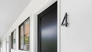 A corridor with white walls, a black door, and a small window. - Modern Harbor Stay | Steps to Tours & Eats (Juneau)