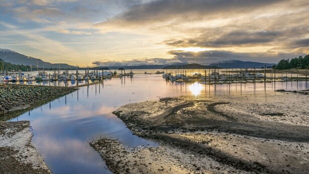 A marina with boats docked, calm water, and a sunset in the background. - Modern Harbor Stay | Steps to Tours & Eats (Juneau)