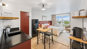 A compact hotel room with a kitchenette, a bed with a view, and a small dining area. - Harbor Hub Retreat | Walk to Tours & Dining (Juneau)