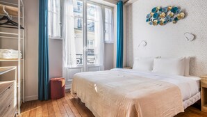 A bedroom with a bed, a wardrobe, and a window with curtains. - Blueground | Sainte-Avoye, view, nr Le Marais (Paris)