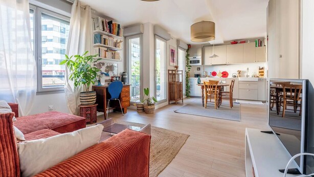 A modern living room with a sofa, a dining table with chairs, a kitchen area, and a TV. - LE CACTUS - Gorge de loup apartment (Lyon)
