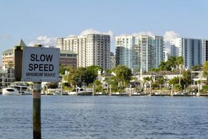 A waterfront view with high-rise buildings, a marina, and a 'SLOW SPEED MINIMUM WAKE' sign.